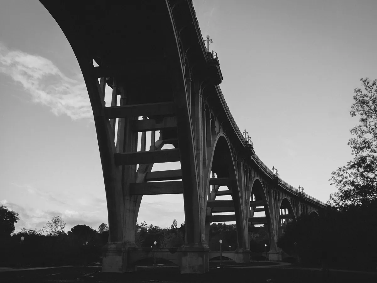 The repeating arches of a concrete viaduct seen from below at dusk